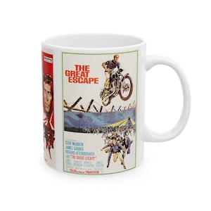 May include: A white ceramic mug featuring a printed movie poster for The Great Escape. The design displays a person riding a motorcycle jumping over a barbed wire fence, a crowd of people running, and the film title in bold red lettering.