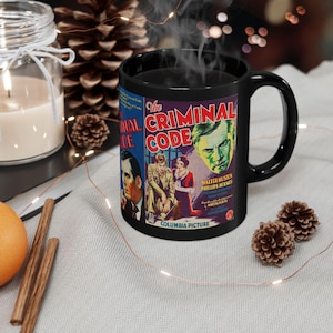 May include: Black ceramic mug featuring a vintage movie poster design for "The Criminal Code." The poster art includes images of actors and the film's title in bold lettering. The mug is on a light gray surface with decorative elements.