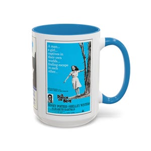 May include: A white ceramic mug with a bright blue interior and handle, featuring a vintage movie poster for A Patch of Blue. The poster displays a woman standing near a tree, with the text A man... a girl... captives in their own worlds.