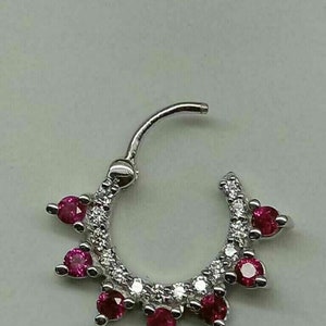 May include: A silver nose ring with a circle of small diamonds and five red ruby stones.