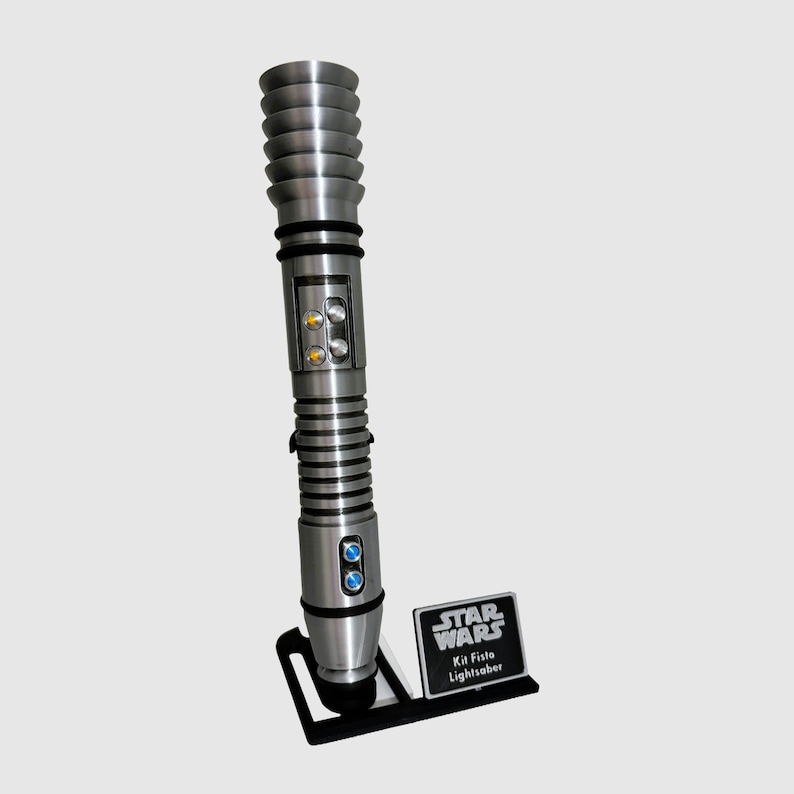 May include: A silver lightsaber with a black handle and a black stand. The stand has a silver plaque that reads "Star Wars" and "Kit Fisto Lightsaber".