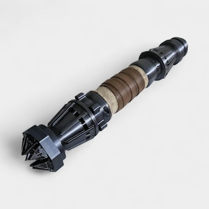 May include: A black and silver metal weapon with a brown leather wrap. The weapon has a pointed tip and a series of metal rings around the handle.