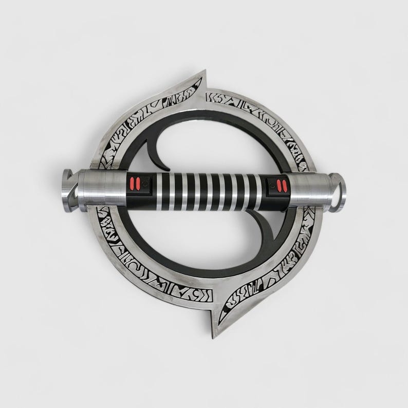 May include: A silver lightsaber with a black handle and red accents. The lightsaber is attached to a circular, silver, metal ring with intricate designs.