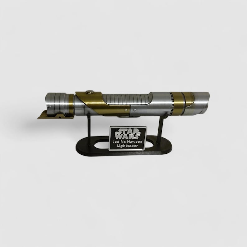 May include: A silver and gold lightsaber with a black stand. The stand has a small plaque that reads "Star Wars Jod Na Nawood Lightsaber".