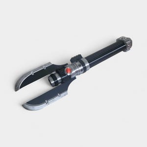 May include: A black and silver prop weapon with two curved blades extending from a central handle. The handle is cylindrical with silver accents and a red button. The blades have a metallic finish.