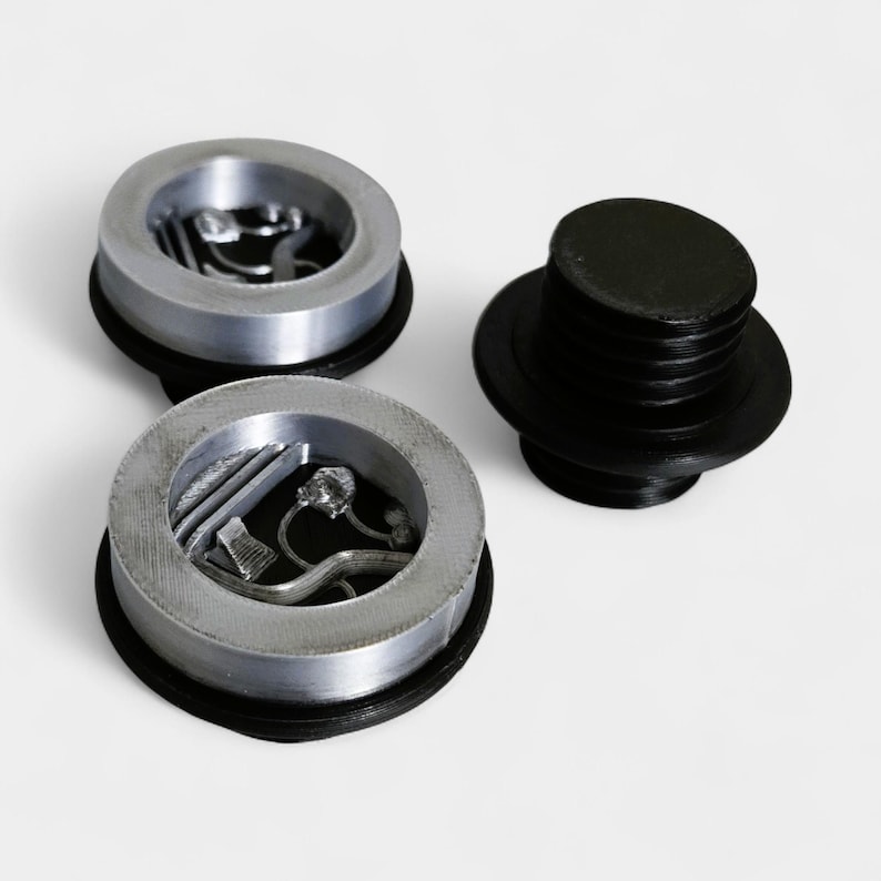 Puede incluir: Tres tapones de botella plateados con bases negras y un tap&oacute;n negro separado. Los tapones plateados tienen un dise&ntilde;o circular con un relieve interior. El tap&oacute;n negro tiene una forma cil&iacute;ndrica con un cuerpo estriado.
