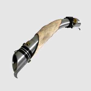 May include: A silver lightsaber with a brown leather-wrapped handle. The lightsaber has a black and silver emitter and a gold accent.