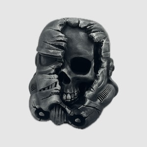 K&ouml;nnte beinhalten: Ein schwarzer und grauer Sch&auml;delhelm mit einem rissigen und zerbrochenen Design. Der Sch&auml;del ist durch die Risse im Helm sichtbar.