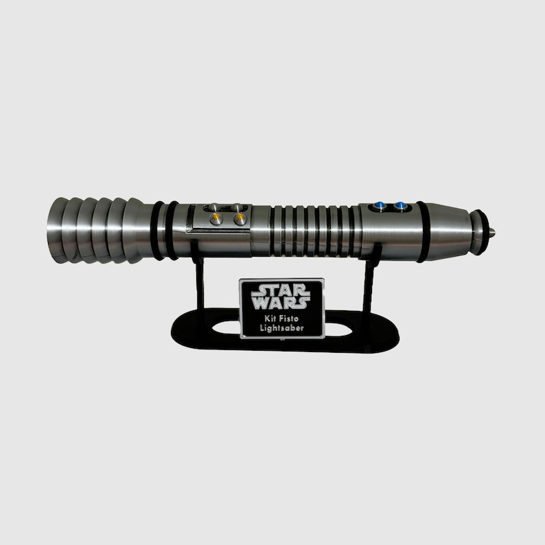 May include: A silver lightsaber with a black stand and a silver plaque that reads "STAR WARS Kit Fisto Lightsaber".