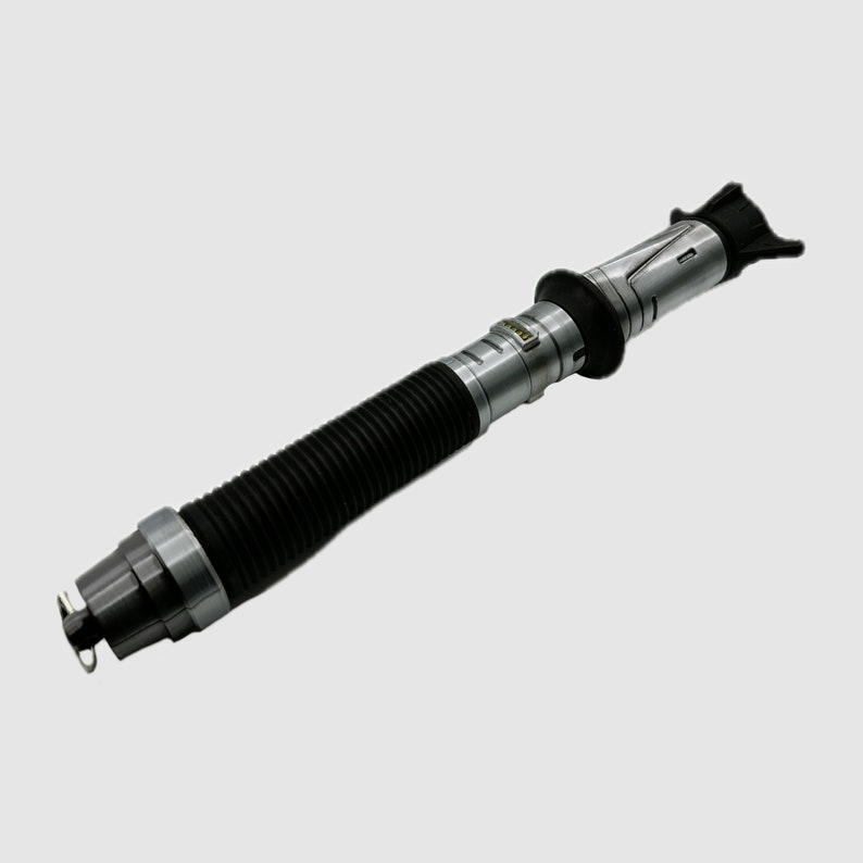 May include: A black and silver telescopic fishing rod with a black rubber grip and a silver metal tip. The rod is extended to its full length.