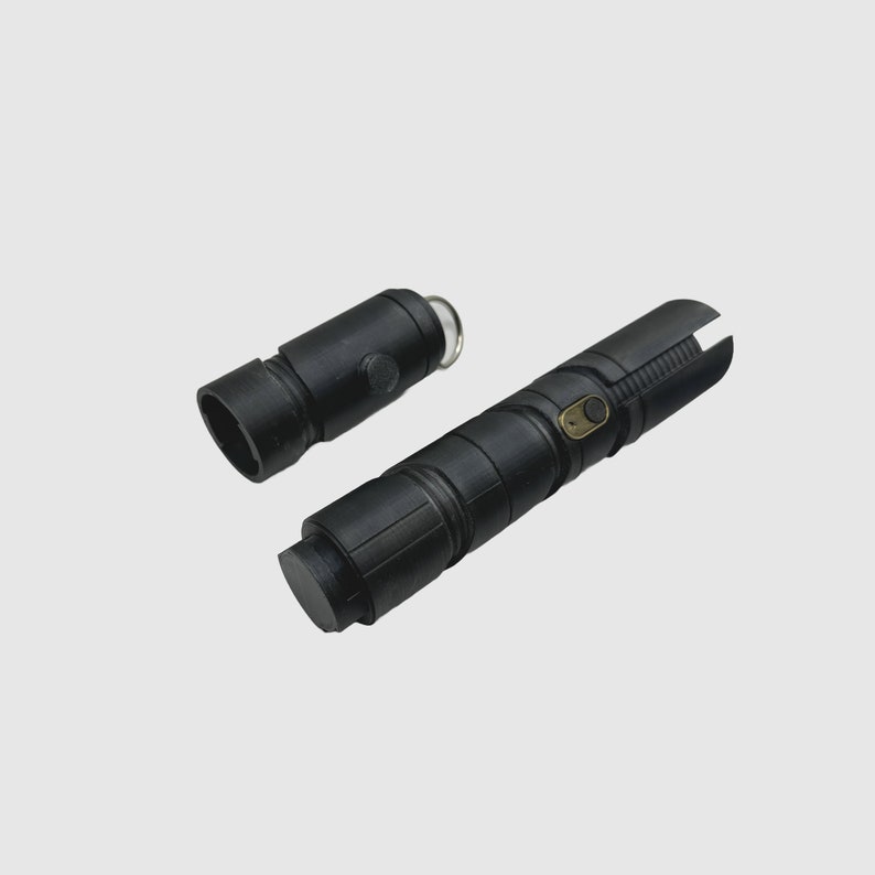 May include: A black lightsaber with a removable handle. The handle has a gold button and a black ring.