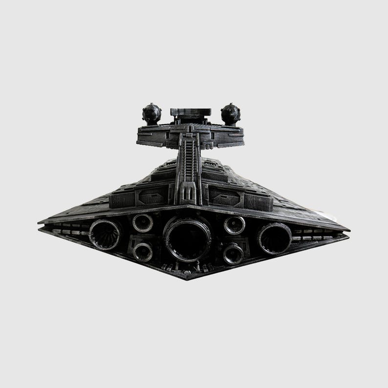 May include: A detailed, dark gray model of a Star Destroyer spaceship. The model features intricate detailing, including multiple circular engine ports and a prominent bridge structure with spherical elements. The ship's design is angular and symmetrical.