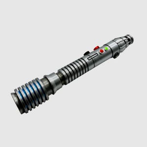 May include: A silver lightsaber with a blue and silver hilt and a red and green button on the side.
