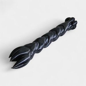 May include: A black, stylized sculpture resembling a clawed hand. The sculpture is made of a glossy material and features a braided design along the shaft. The clawed end has three sharp points.