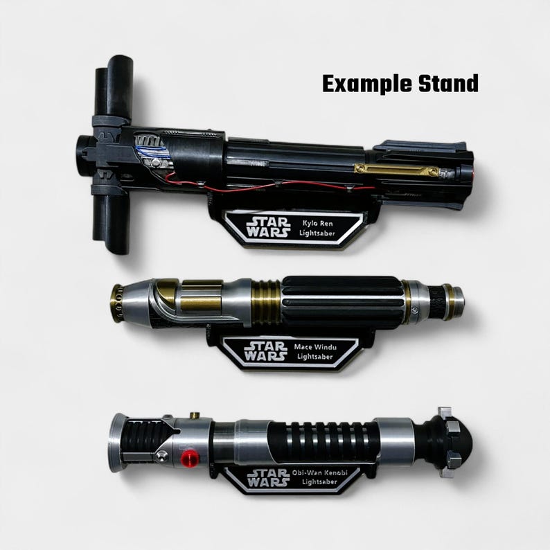 May include: Three Star Wars lightsabers, including Kylo Ren, Mace Windu, and Obi-Wan Kenobi models, displayed on black stands. The lightsabers are black, silver, and gold, with intricate detailing. The stands feature the Star Wars logo and character names.