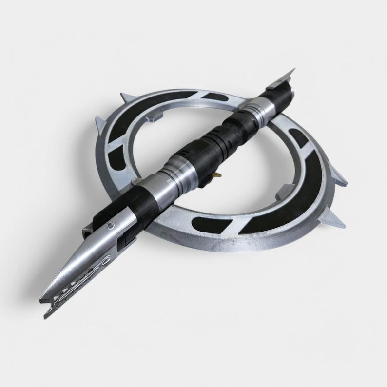 May include: A silver and black lightsaber with a circular guard. The lightsaber is in a defensive position with the blade retracted.
