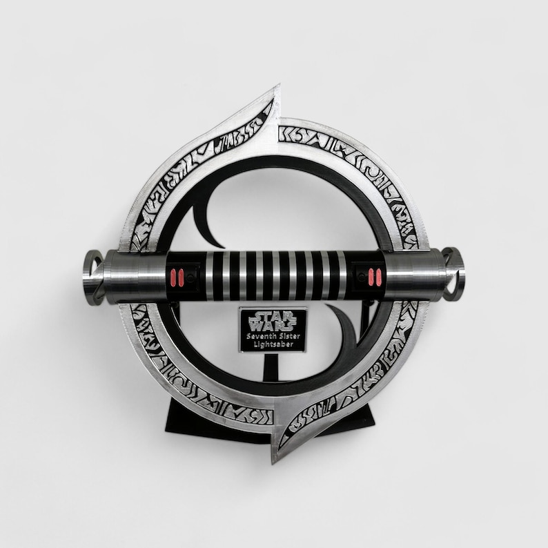 May include: A silver lightsaber with black accents and red buttons, mounted on a circular stand with intricate engravings. The stand has a black plaque with the text "STAR WARS Seventh Sister Lightsaber".