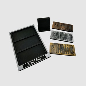 May include: A silver tray with three compartments labeled "Credit Chip".  The tray is used to hold three credit chips, each with a different design. The chips are made of wood and have a black and white design.