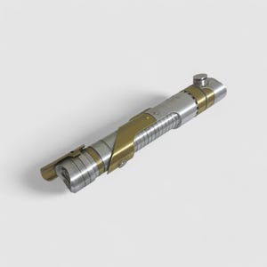 May include: A silver and gold lightsaber with a textured handle and a black button on the end.
