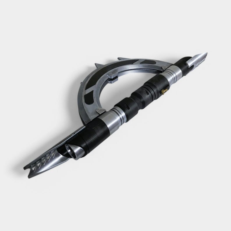 May include: A silver and black lightsaber with a curved handle and a sharp blade. The lightsaber is designed to look like a weapon from a science fiction film.