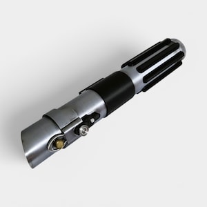 May include: A silver and black lightsaber prop with a black handle and a silver blade. The handle has a black grip and a silver metal band.
