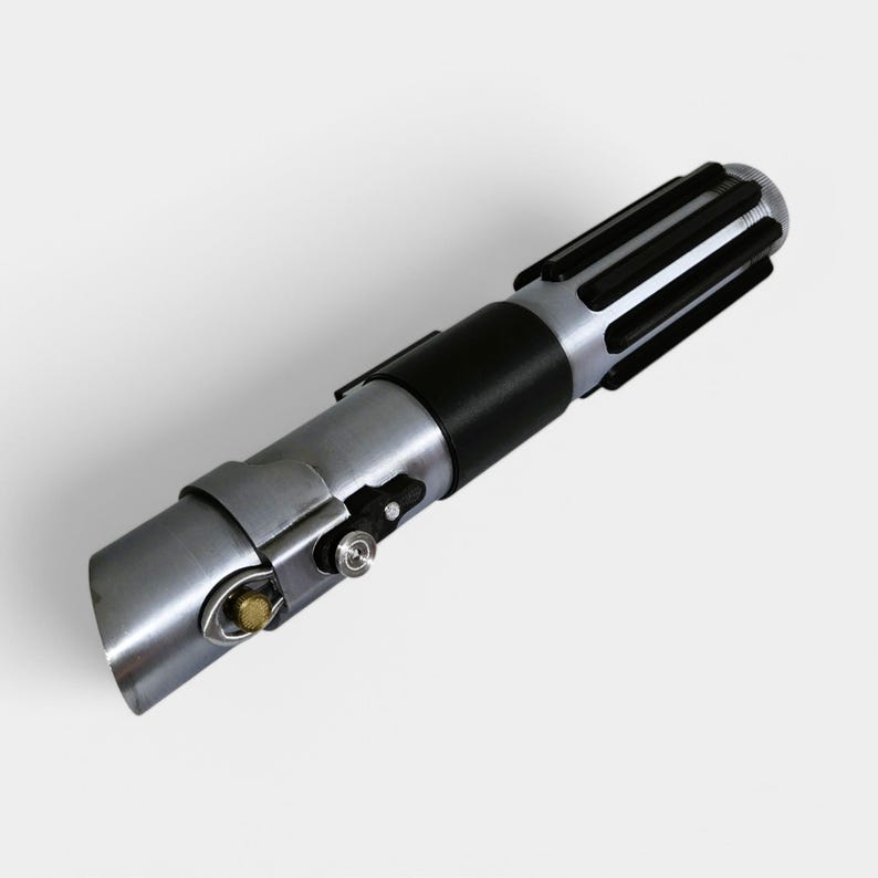 May include: A silver and black lightsaber prop with a black handle and a silver blade. The handle has a black grip and a silver metal band.