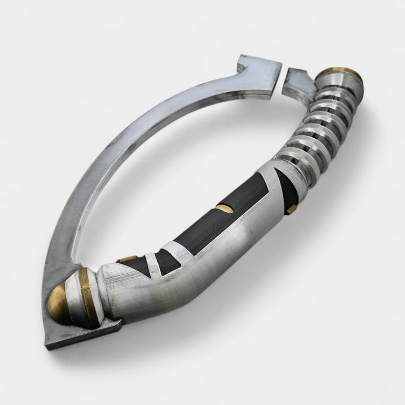 May include: A silver and black lightsaber hilt with a curved handle. The hilt features a black grip with silver accents, a ribbed section, and gold-colored details. The design is futuristic and detailed.
