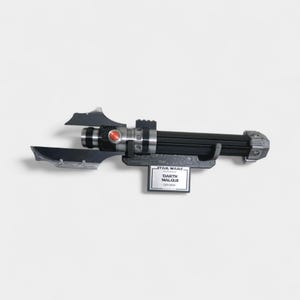 May include: A black and silver lightsaber prop with a red button and a silver handle. The lightsaber is mounted on a black stand with a Star Wars label that reads "Darth Malgus Lightsaber."