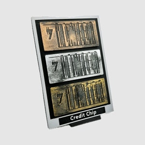 May include: A black plastic credit chip holder with three different coloured credit chips. The chips are silver, gold, and bronze. Each chip has a number "7" and a barcode pattern.