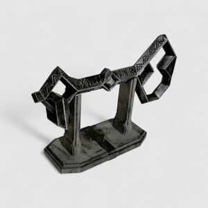 May include: A black metal key-shaped stand with intricate details. The stand is designed to hold a pair of keys or other small objects.