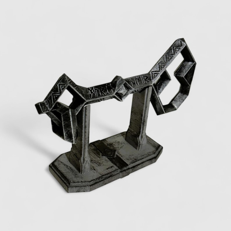May include: A black metal key-shaped stand with intricate details. The stand is designed to hold a pair of keys or other small objects.