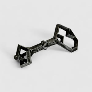 May include: A silver-colored metal key with a geometric design. The key has a long, narrow shaft and a large, intricate head.