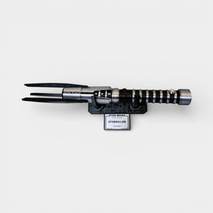 Op de afbeelding: Een Star Wars Starkiller lichtzwaard replica. Het lichtzwaard heeft een zwart en zilveren handvat met een geribbelde grip en een drietandig blad. Het is gemonteerd op een zwarte basis met een Star Wars logo en een Starkiller naamplaatje.