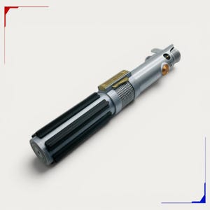 May include: A silver-toned cylindrical prop handle featuring a black-ribbed grip section, a textured metallic mid-section, and a gold-colored rectangular control plate. The upper portion includes a circular orange button and a small metallic lever.