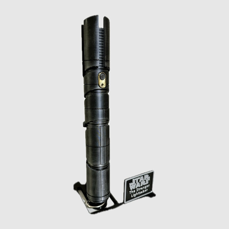 May include: A black lightsaber with a gold accent and a silver plaque that reads "STAR WARS The Stranger Lightsaber".