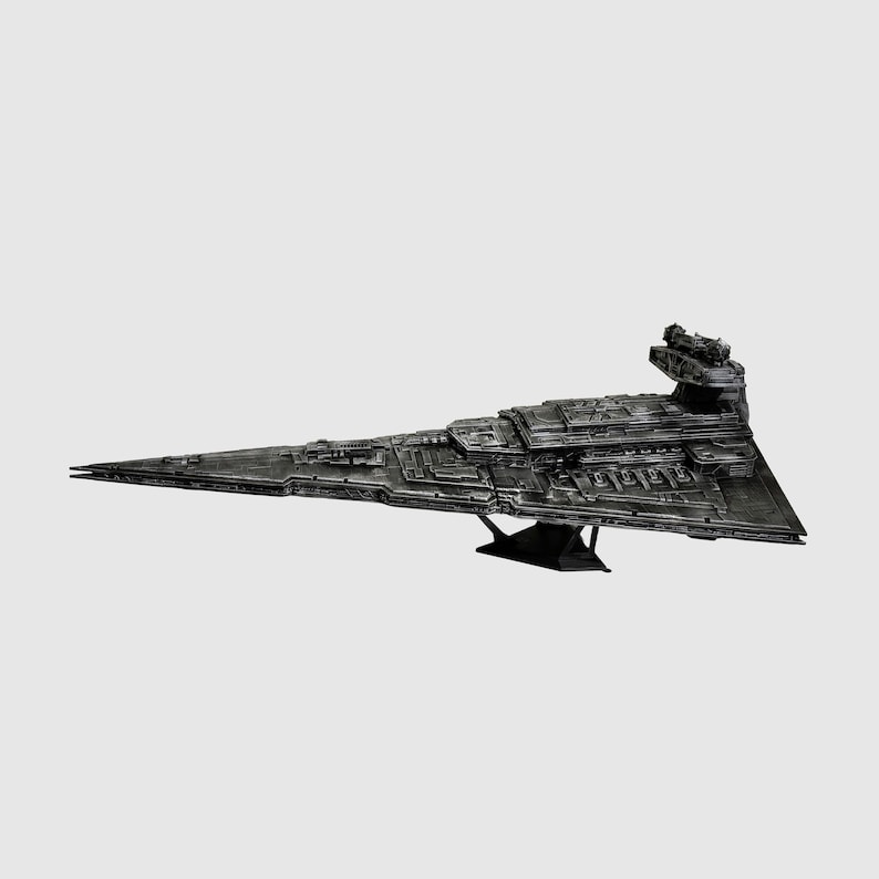 May include: A detailed, dark gray model of a Star Destroyer spaceship. The model is triangular with intricate surface details, a prominent command tower, and is mounted on a black stand. The spaceship is a replica of a fictional spacecraft.