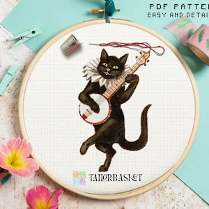 Puede incluir: Patrón de punto de cruz con un gato negro tocando un banjo. El gato lleva un cuello blanco y tiene una expresión traviesa. El patrón se titula "Tailorbasket" y está disponible para descargar en PDF.