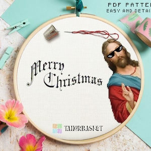 May include: A cross-stitch pattern featuring a portrait of Jesus wearing sunglasses with the text "Merry Christmas" in a gothic font.