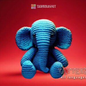 Puede incluir: Un juguete de amigurumi de elefante de crochet azul sentado sobre un fondo rojo. El texto "PATTERN all languages" está en la parte inferior de la imagen.