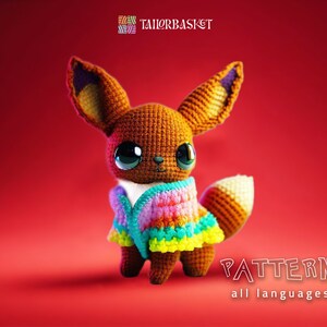 Könnte beinhalten: Ein gehäkeltes Amigurumi-Spielzeug eines braunen Fuchses mit einer regenbogenfarbenen gehäkelten Jacke. Das Spielzeug steht auf einem roten Hintergrund. Der Text "PATTERN all languages" befindet sich am unteren Rand des Bildes.