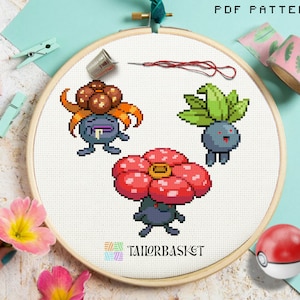 Peut inclure: Modèle de point de croix représentant trois personnages Pokémon : un Vileplume brun et orange, un Oddish vert et violet et un Victreebel rouge et noir. Le modèle est présenté dans un cerceau à broder en bois.