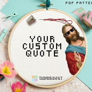 May include: A white embroidery hoop with a cross-stitch pattern that says "YOUR CUSTOM QUOTE" and a pixelated image of Jesus wearing sunglasses. The hoop is on a light blue background with pink flowers.