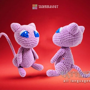 May include: A purple crocheted plush toy resembling a cat with blue eyes. The toy is sitting on a red background. The text "PATTERN all languages" is visible at the bottom of the image.