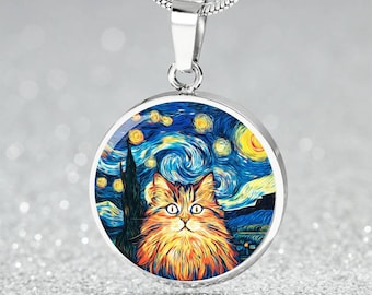 May include: A silver pendant necklace featuring a round charm with a cat portrait set against a starry night sky background. The cat has orange and yellow fur, and the background is a swirling blue and yellow design.