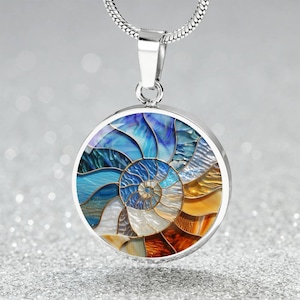 May include: A silver pendant necklace featuring a round, mosaic-style design. The pendant showcases a spiral pattern in shades of blue, white, and orange, resembling a nautilus shell. The necklace has a silver chain.