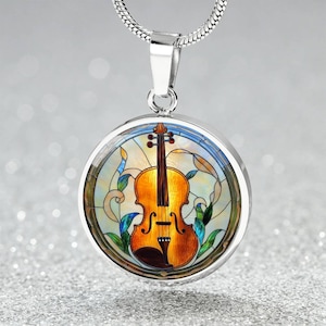May include: A silver-toned pendant necklace featuring a round charm with a stained-glass design. The charm showcases a detailed violin in shades of brown and gold, surrounded by colorful floral accents. The necklace has a delicate chain.