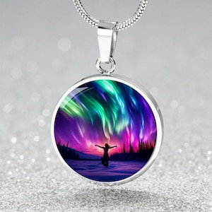 May include: A silver necklace with a round pendant featuring a colorful aurora borealis scene with a silhouette of a person with arms outstretched.