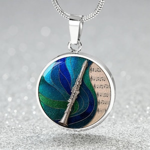 May include: Silver-toned pendant necklace featuring a clarinet design. The round pendant has a blue and green abstract background, a clarinet, and sheet music. The necklace is on a silver chain.