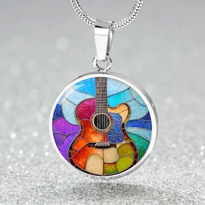 May include: A silver necklace with a round pendant featuring a colorful stained glass design of an acoustic guitar. The guitar is depicted in shades of blue, purple, green, yellow, orange, and red.