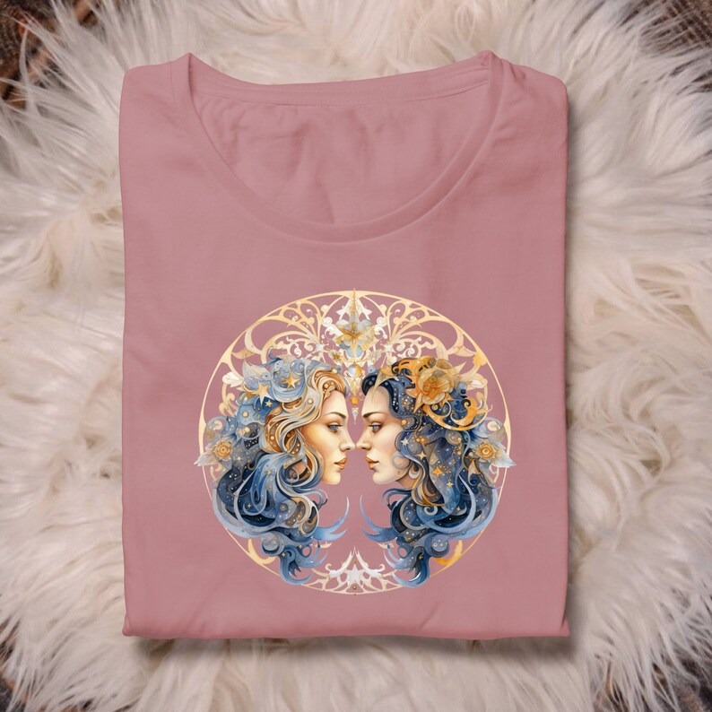 Może przedstawiać: R&oacute;żowy t-shirt z złotą i niebieską ilustracją dw&oacute;ch kobiecych twarzy otoczonych okrągłym wzorem. Włosy kobiet są ozdobione gwiazdami i kwiatami.